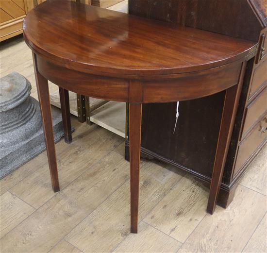 A George III line inlaid mahogany D shaped folding tea table, on square tapered legs W.89cm